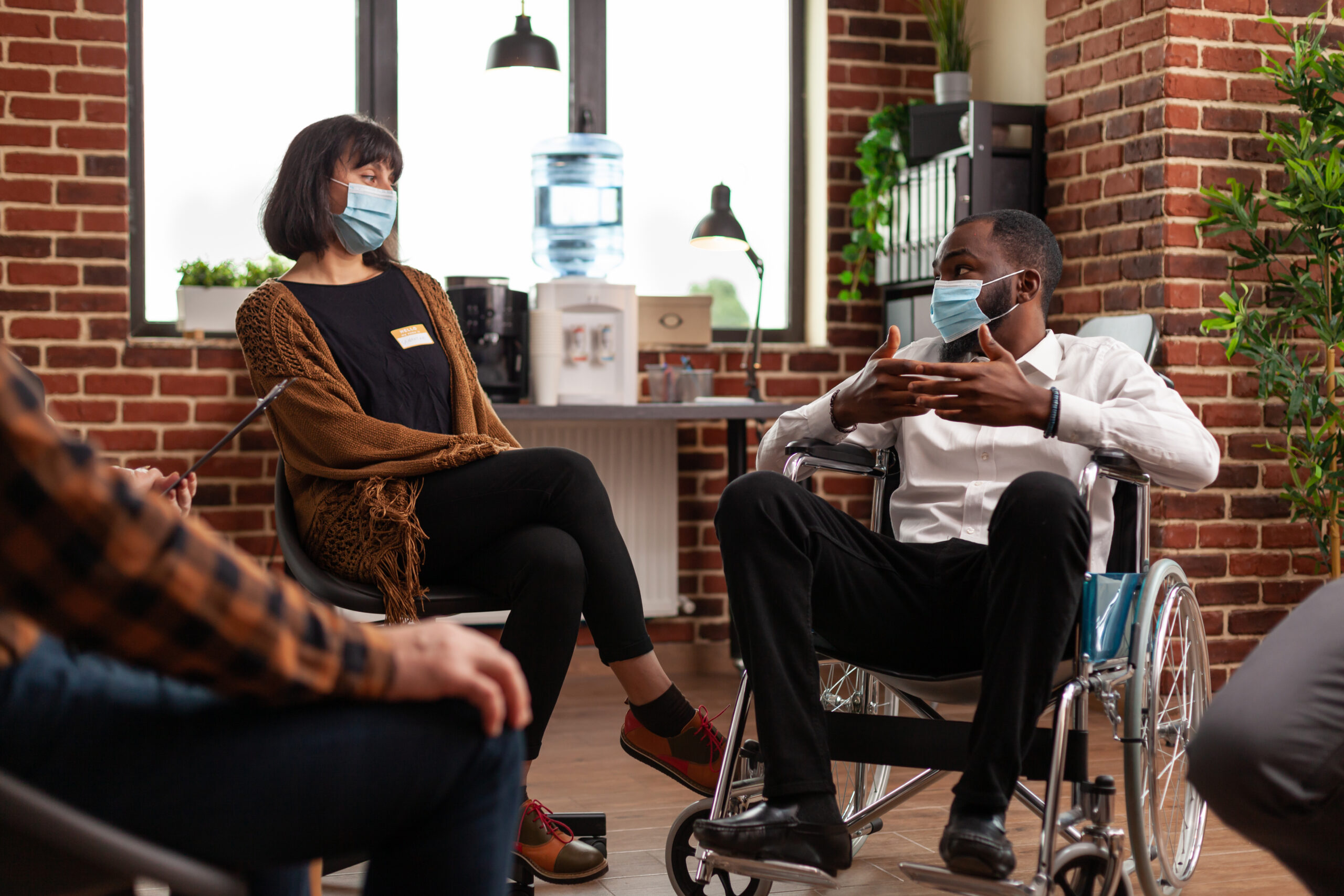 Man with disability talking at group therapy session with people having alcohol addiction